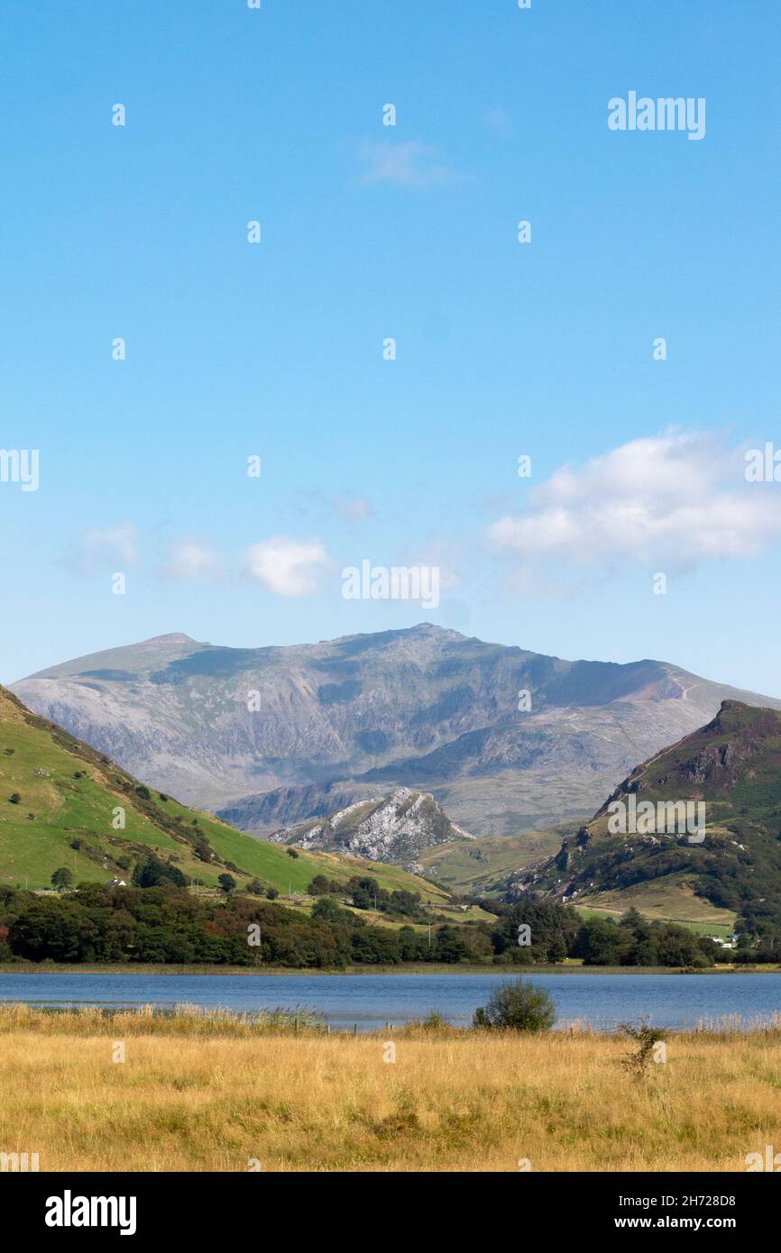 Bellissimo lago Nantlle, Snowdonia, Galles. Scatto verticale con primo piano di acqua e prato. Spettacolare e robusto Mount Snowdon sullo sfondo. Copia sp Foto Stock