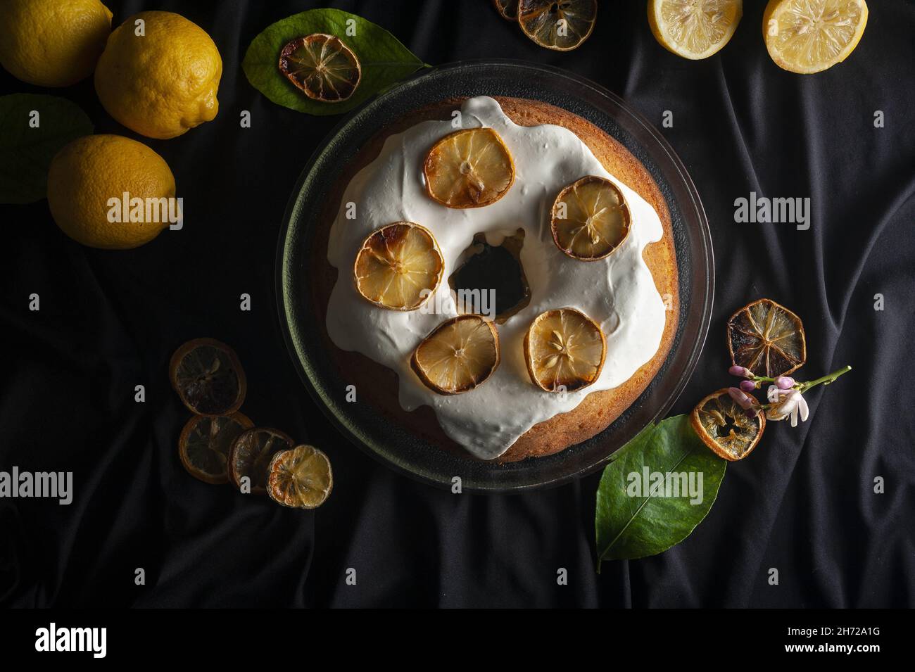 Deliziosa torta agli agrumi con una decorazione di fette di limone secco su sfondo nero. Foto Stock
