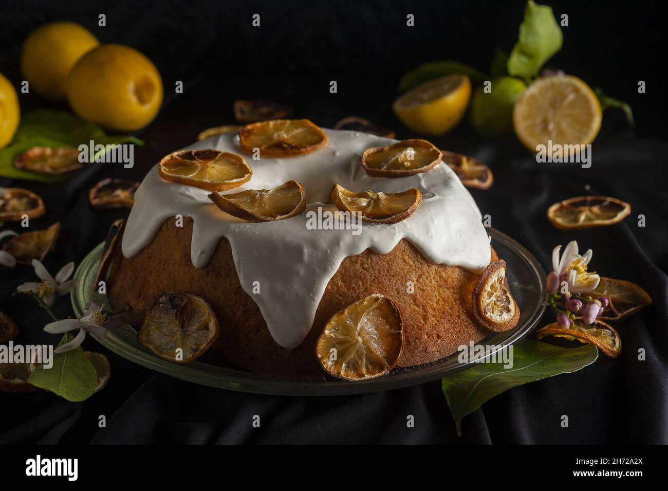 Deliziosa torta agli agrumi con una decorazione di fette di limone secco su sfondo nero. Foto Stock