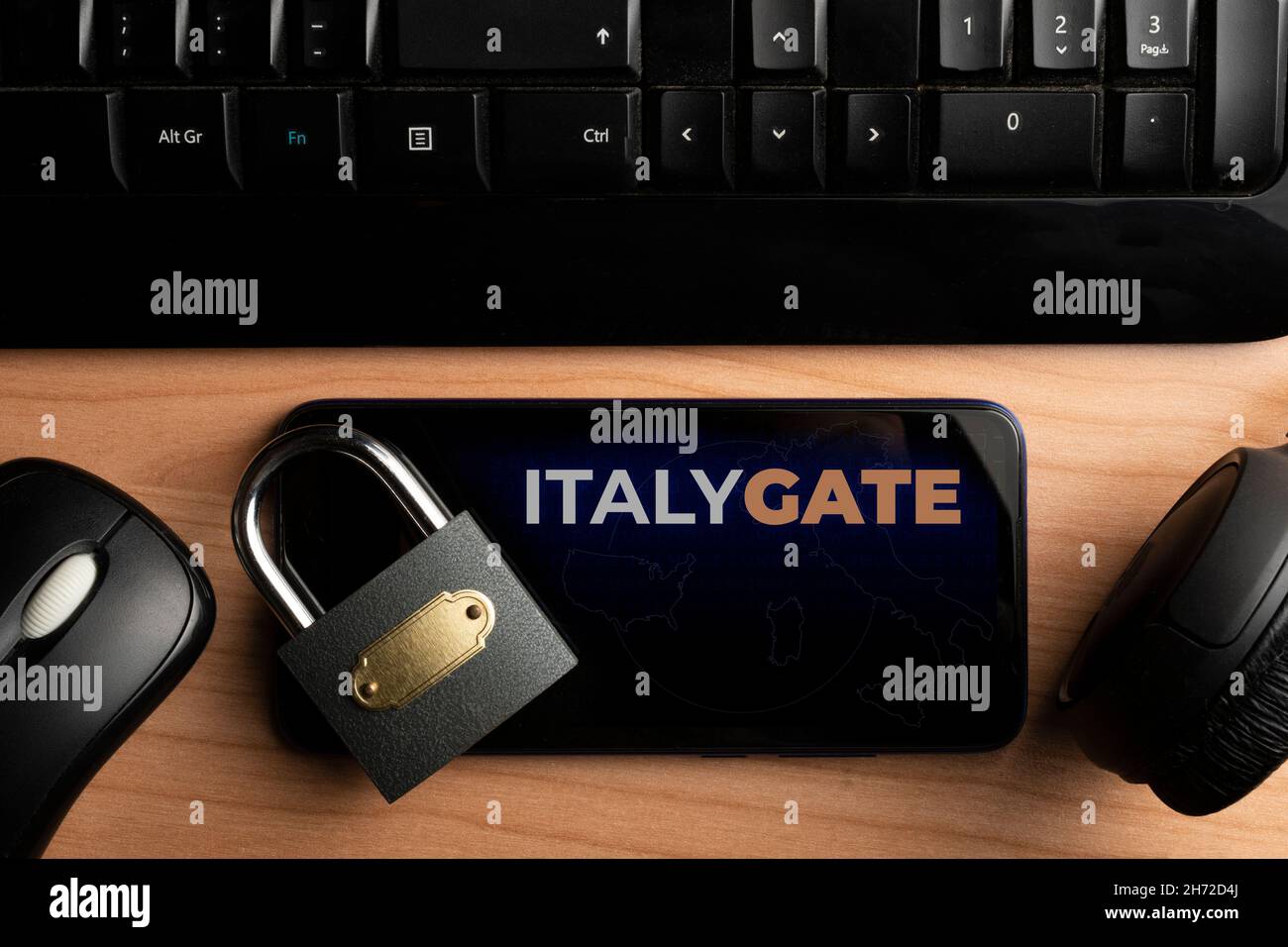 Concetto Italygate: Smartphone su tavolo in legno con mouse, tastiera per computer e un paio di cuffie Foto Stock