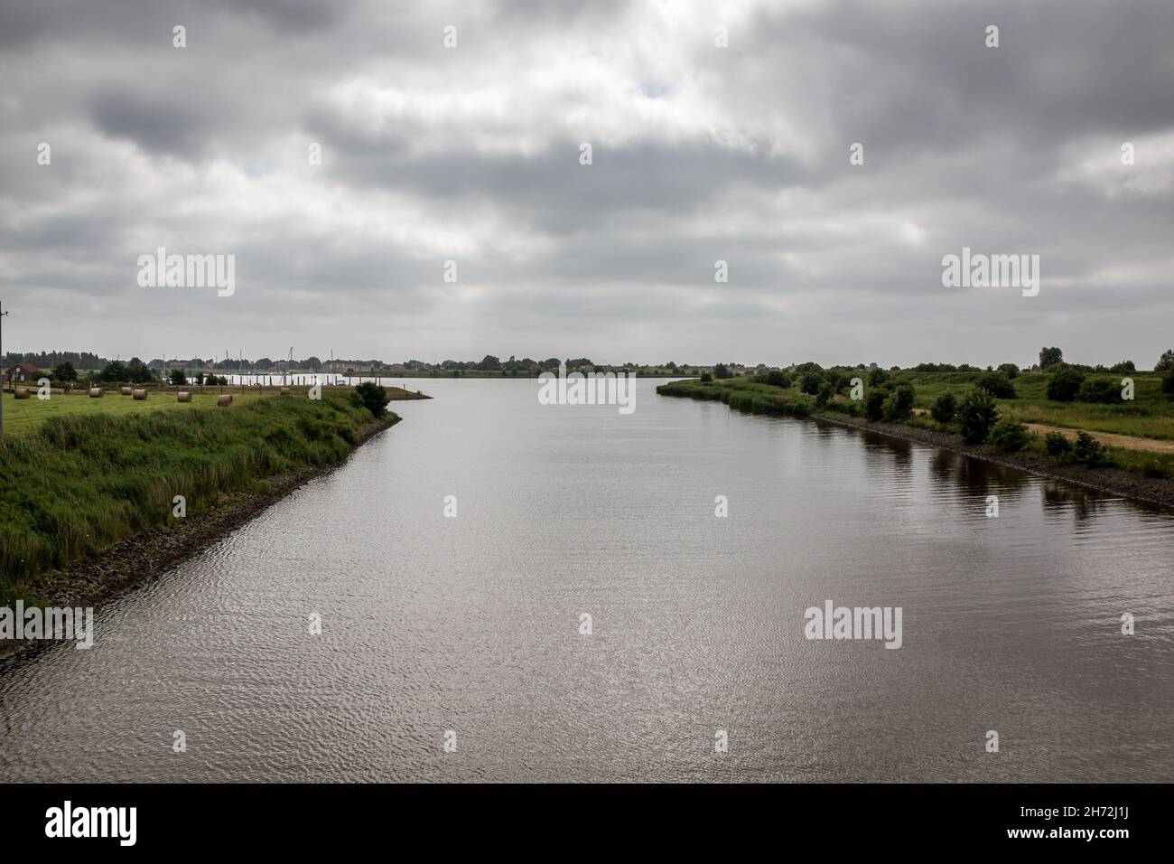 Fiume attraverso campi verdi di erba nel mezzo della campagna Foto Stock