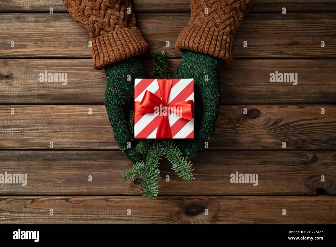 Scatola regalo di Natale nelle mani di una donna su sfondo vintage in legno Foto Stock