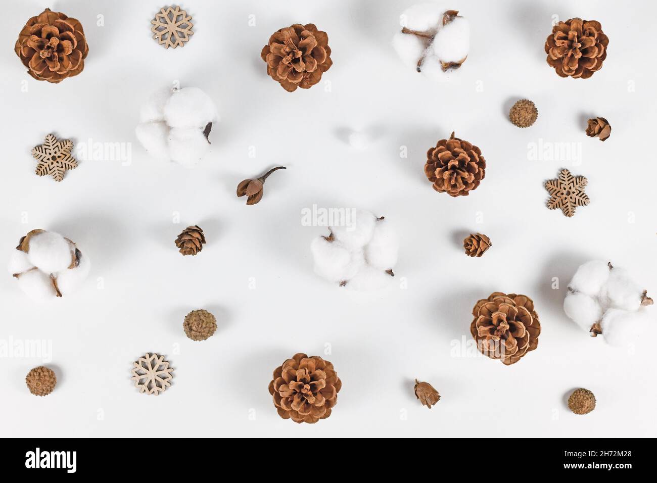 Sistemazione invernale con coni di abete, ornamenti in fiocco di neve e Gossypium di cotone su sfondo bianco Foto Stock