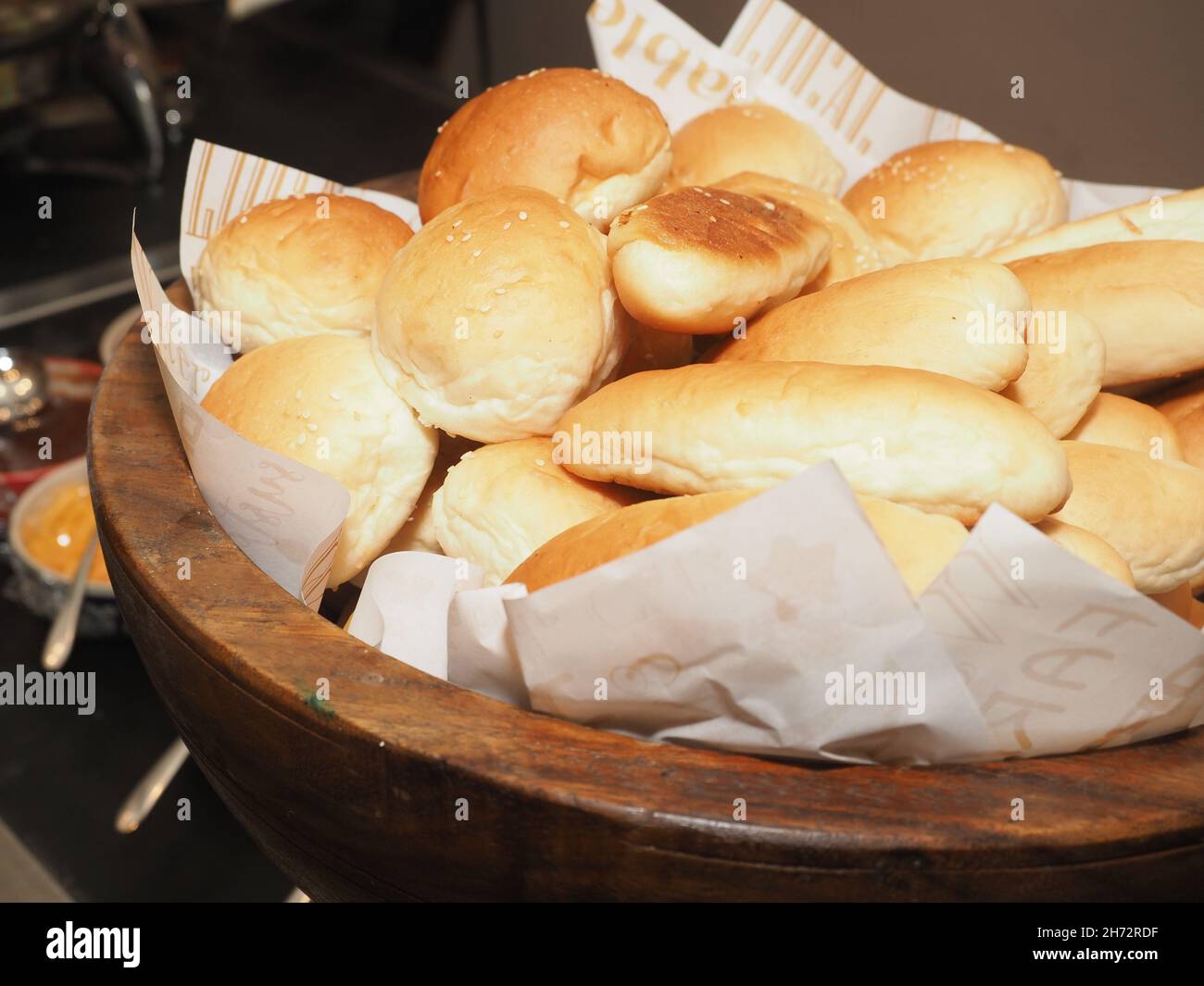 Primo piano di panini appena sfornati su una ciotola di legno con ingredienti alimentari sullo sfondo Conc Foto Stock