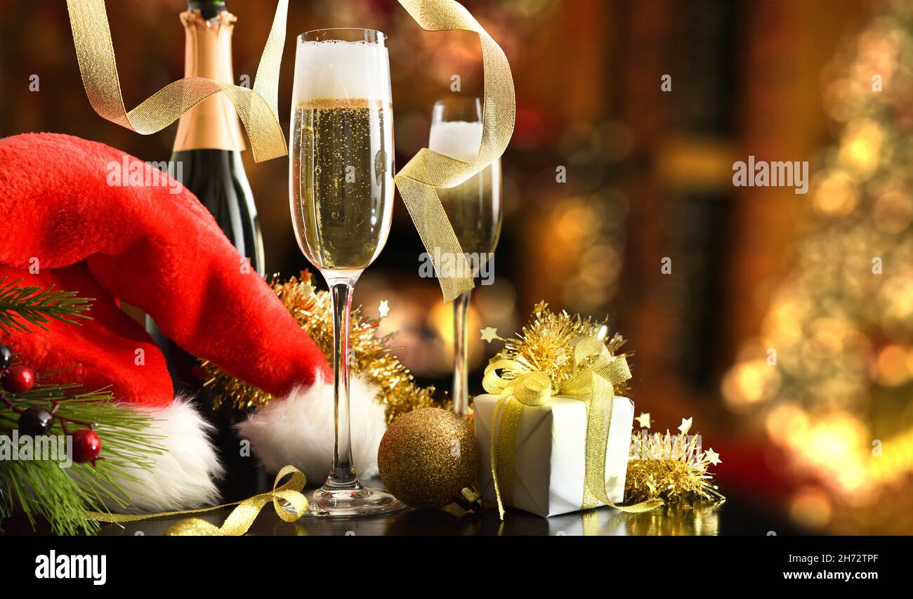 Concetto di festa di Natale con bottiglia di vino bianco frizzante e bicchieri e cappello di natale con regalo e decorazione a nastro lucido in livi Foto Stock