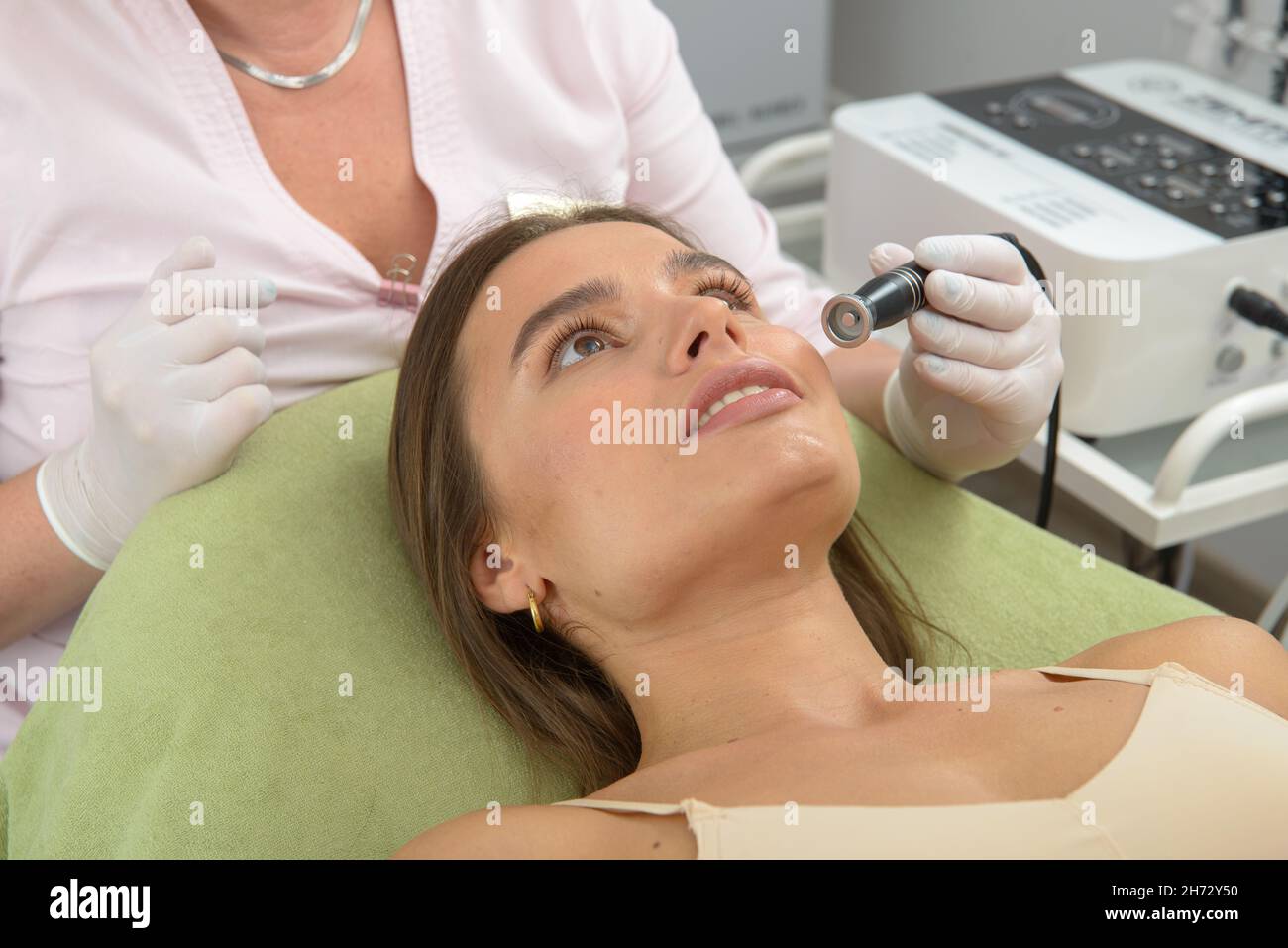 Mesoterapia non iniettabile. Medico e paziente in clinica. Strumento di cosmetologia del ringiovanimento. Donna estetica pelle viso procedura. Foto Stock