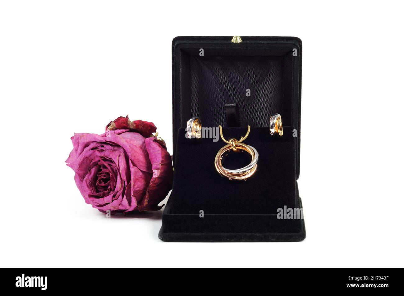 Una scatola di gioielleria aperta con gioielli in oro e platino con rosa secca, su bianco Foto Stock