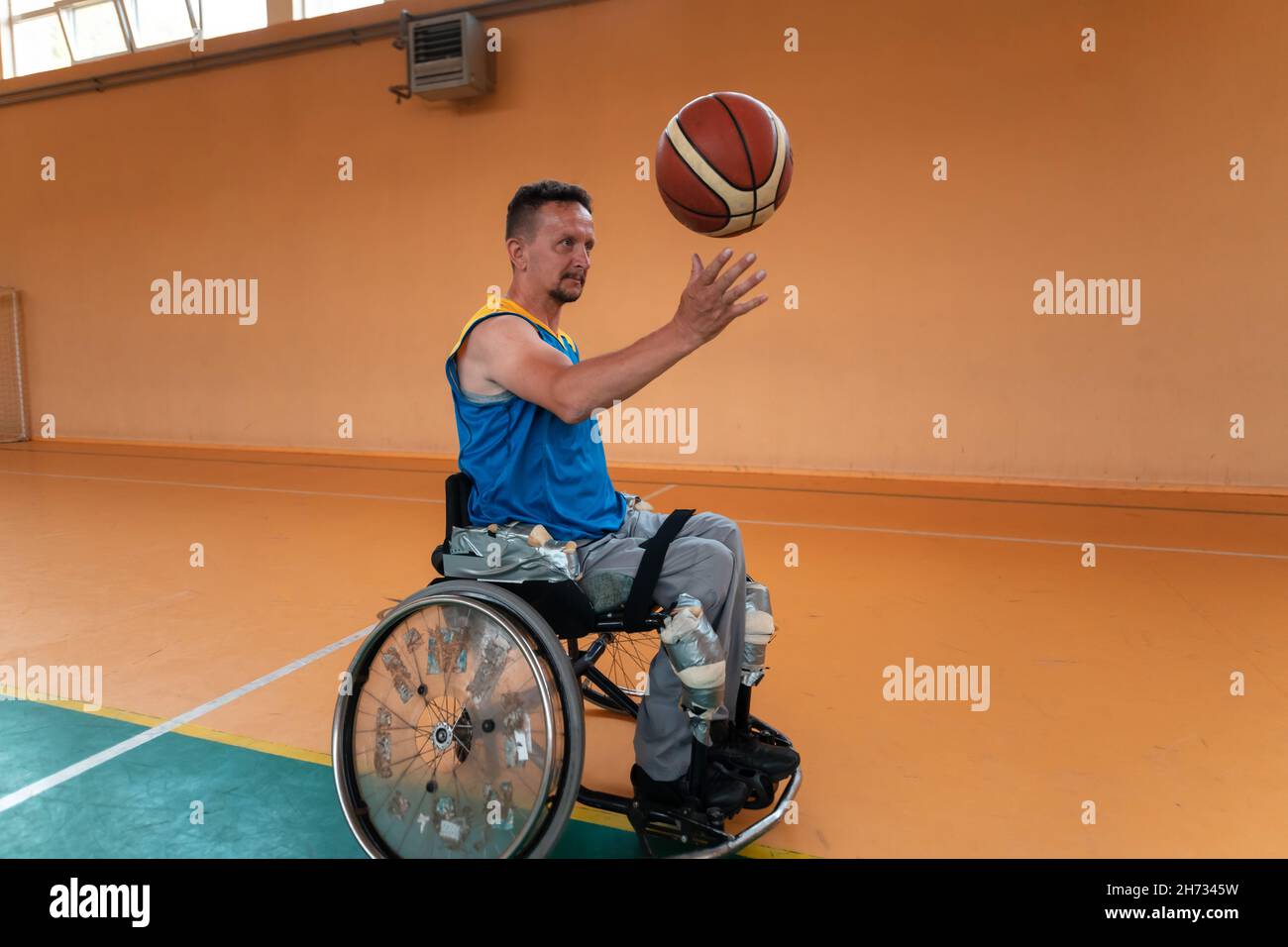 I veterani della guerra disabili hanno mescolato le squadre di pallacanestro di età e di corsa in carrozzina che giocano un match di addestramento in una sala della palestra di sport. Disabili Foto Stock