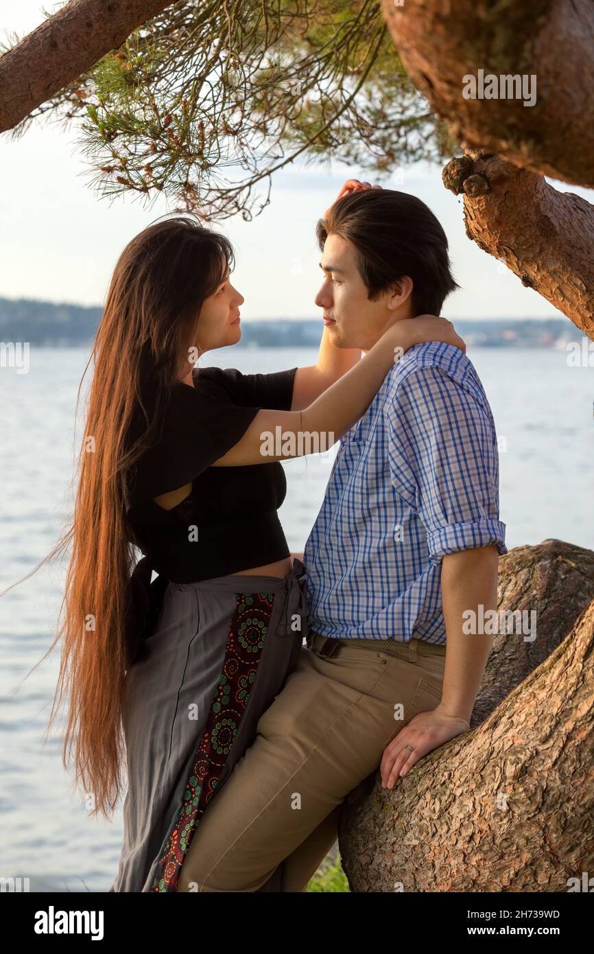 Goodlooking giovane biraciale asiatico caucasico misto coppia di corsa godendo insieme tempo dal lago al tramonto nel nord-ovest del Pacifico Foto Stock