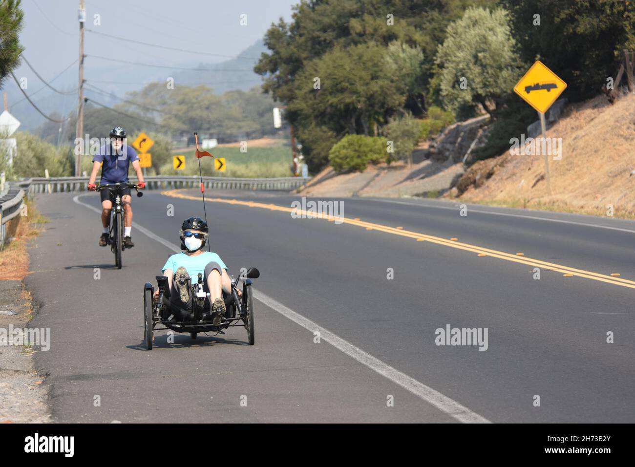 Cavalcando la pista ciclabile di Silverado nella regione vinicola della Napa Valley nella California settentrionale, in bicicletta normale e in bicicletta ricombinante, tra uva da vino e auto Foto Stock