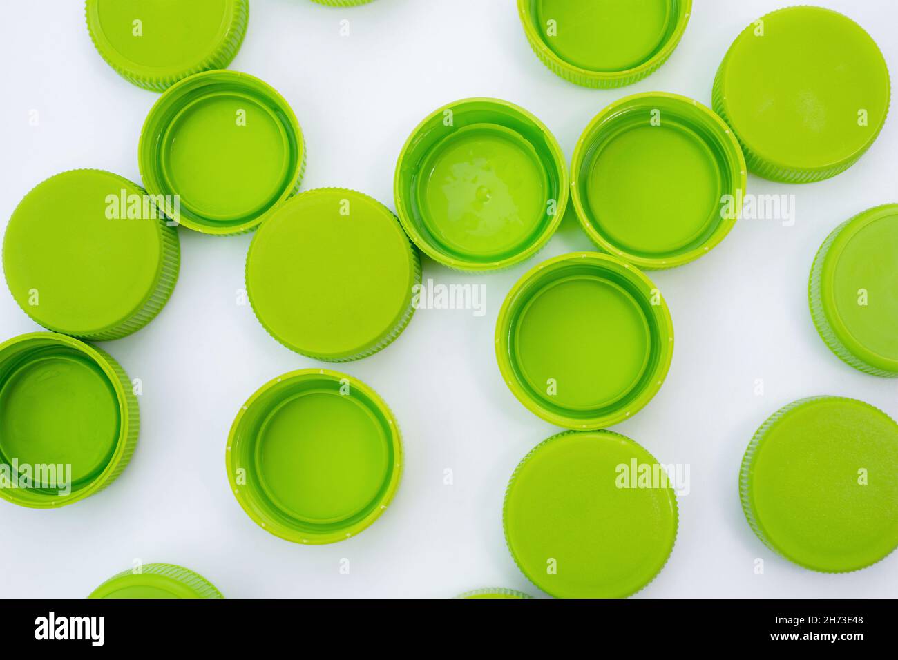 Tappi verdi da bottiglie di plastica su fondo bianco piatto Foto Stock