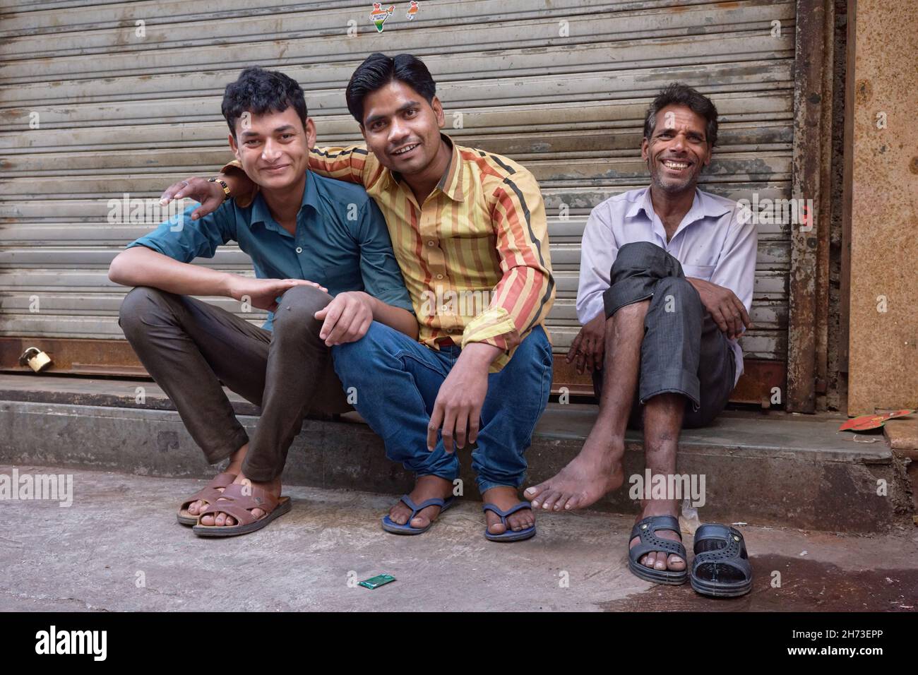 In una domenica libera dal lavoro, i lavoratori migranti provenienti dallo stato dell'India settentrionale Uttar Pradesh si rilassano nella zona mercantile di Zaveri Bazar a Mumbai, India Foto Stock