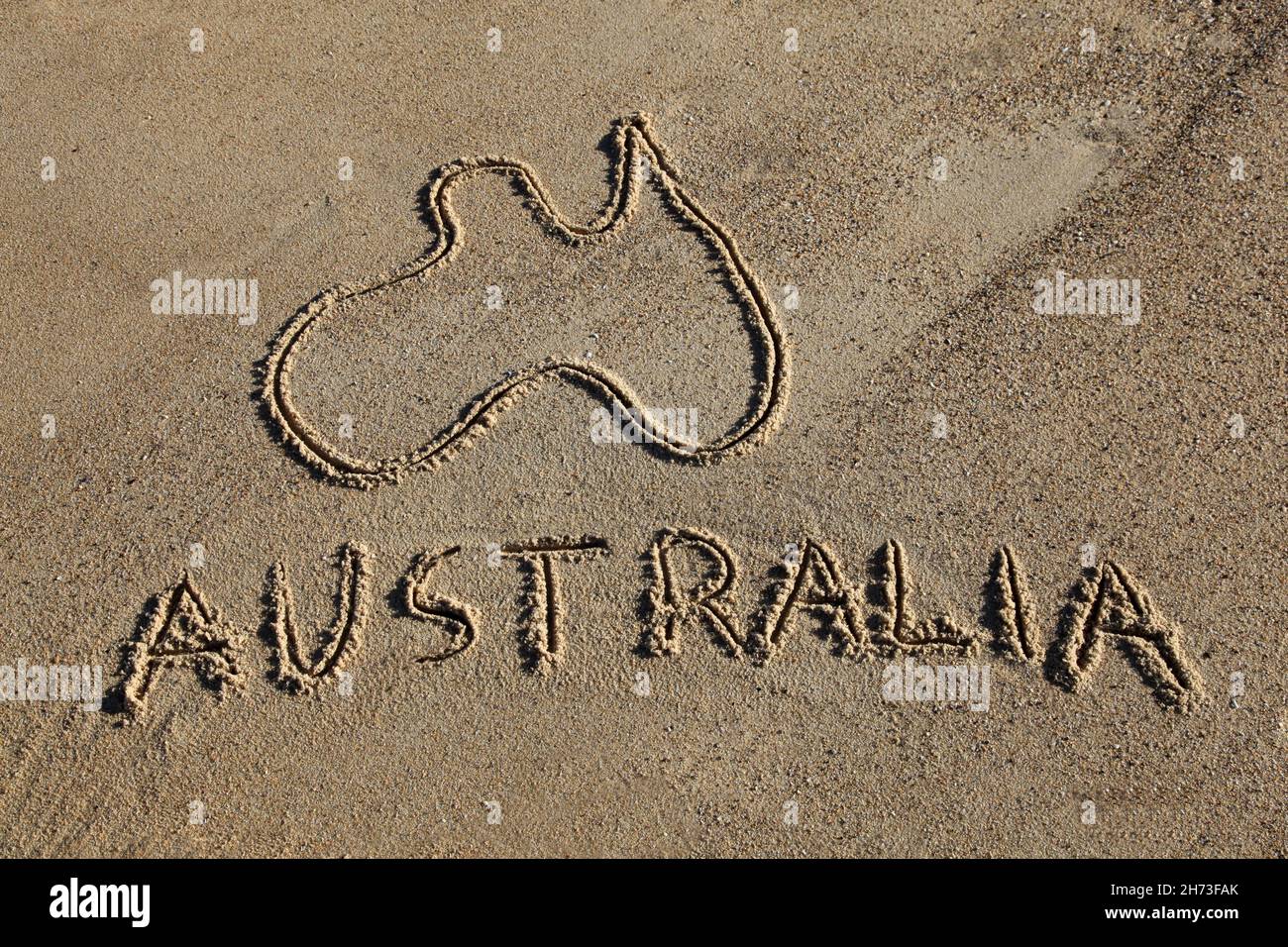 Australia Mappa e parola disegnata nella sabbia alla spiaggia. Le spiagge australiane sono una delle sue iconiche carte da disegno. Foto Stock