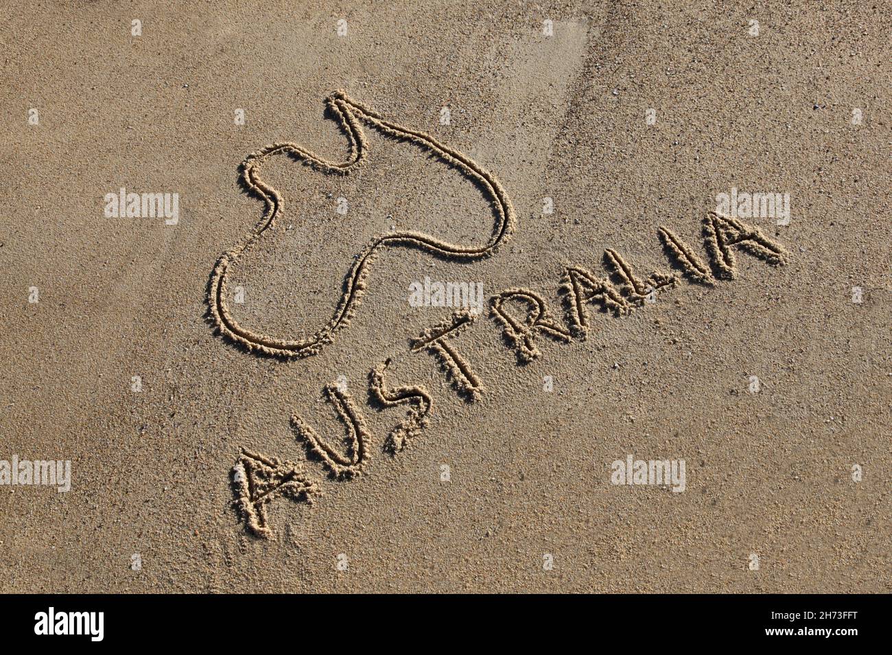 Australia Mappa e parola disegnata nella sabbia alla spiaggia in un angolo. Le spiagge australiane sono una delle sue iconiche carte da disegno. Foto Stock