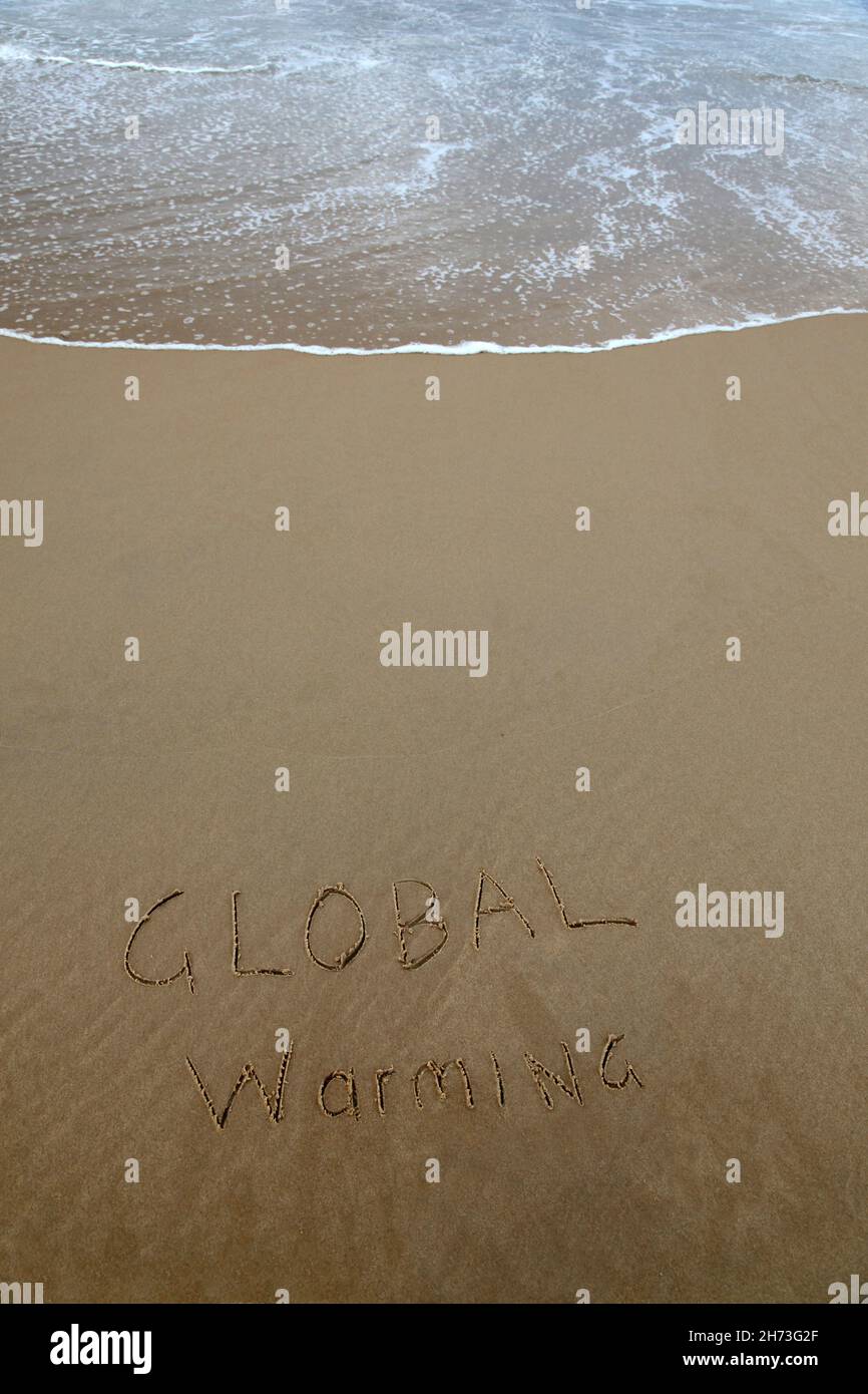 Riscaldamento globale scritto nella sabbia in spiaggia con l'onda ascendente Foto Stock