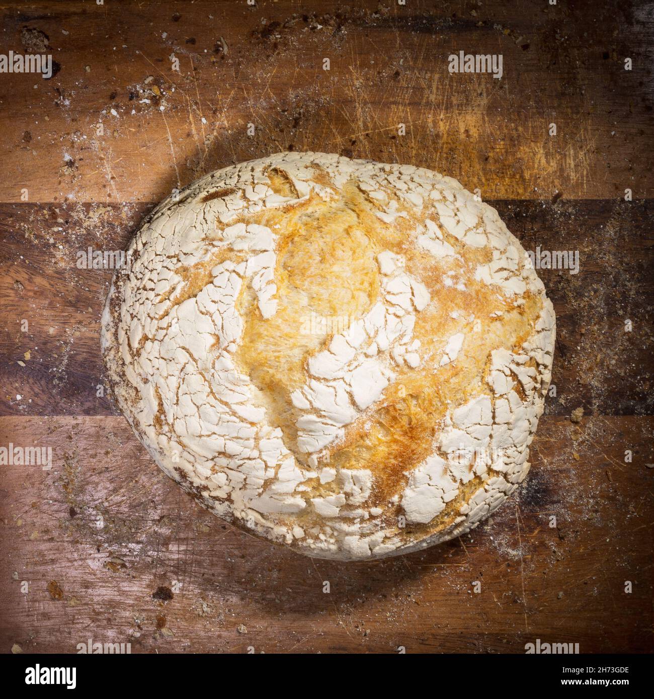 Pane appena sfornato su una tavola di legno con briciole di pane Foto Stock