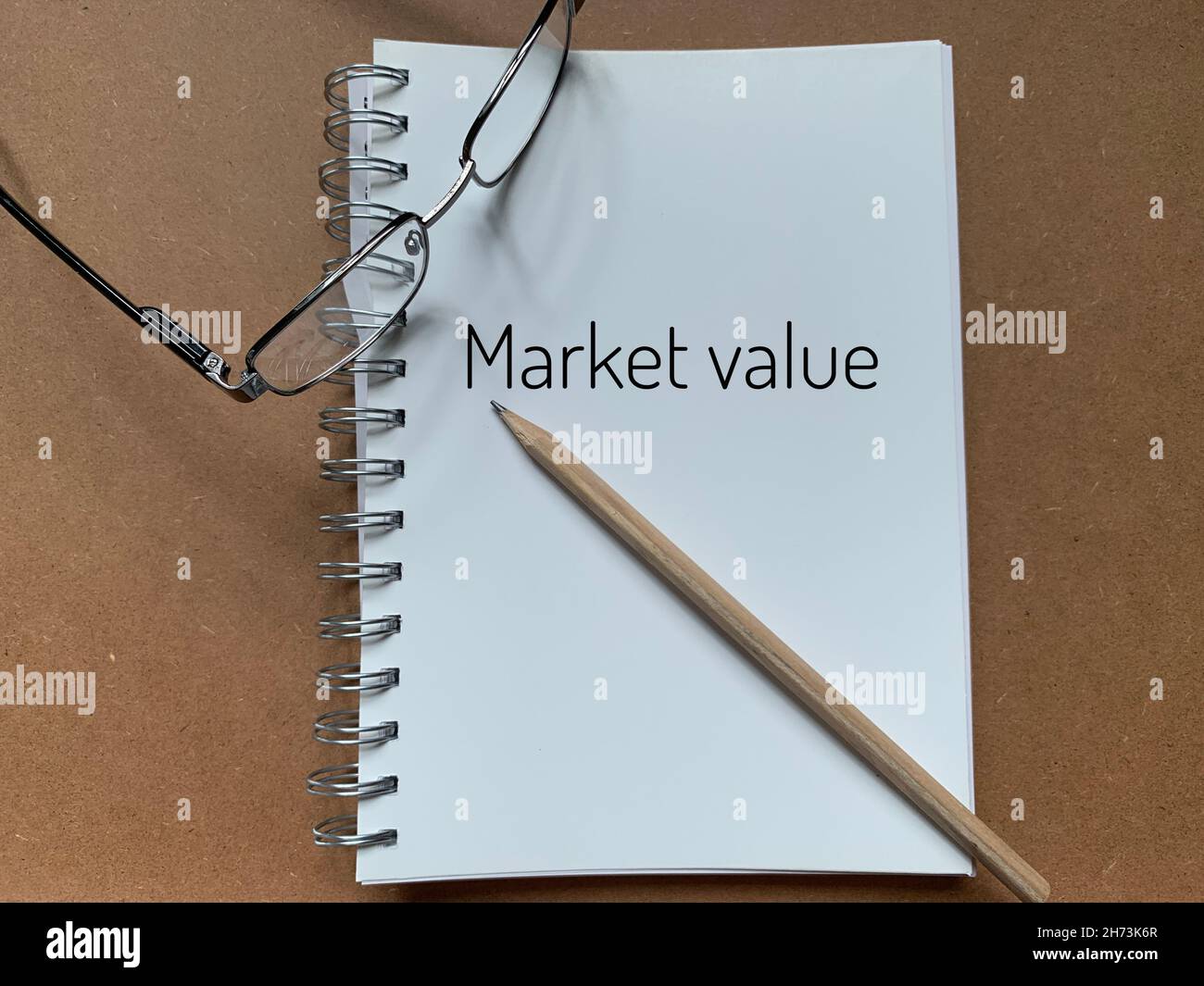 Valore di mercato scritto su un blocco note con matita e occhiali nell'immagine Foto Stock