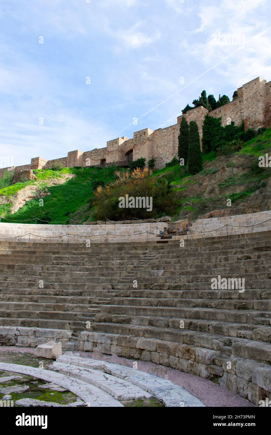 Bellissimo teatro storico romano, Malaga, Spagna. Verticale girato con l'antico monumento in primo piano, e il palazzo moresco Alcazaba nel bac Foto Stock