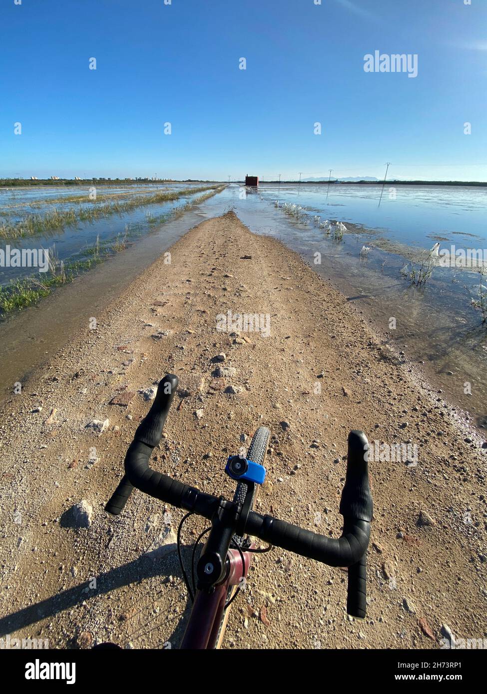 Punto di vista del ciclista in una strada polverosa chiusa da alluvioni d'acqua Foto Stock