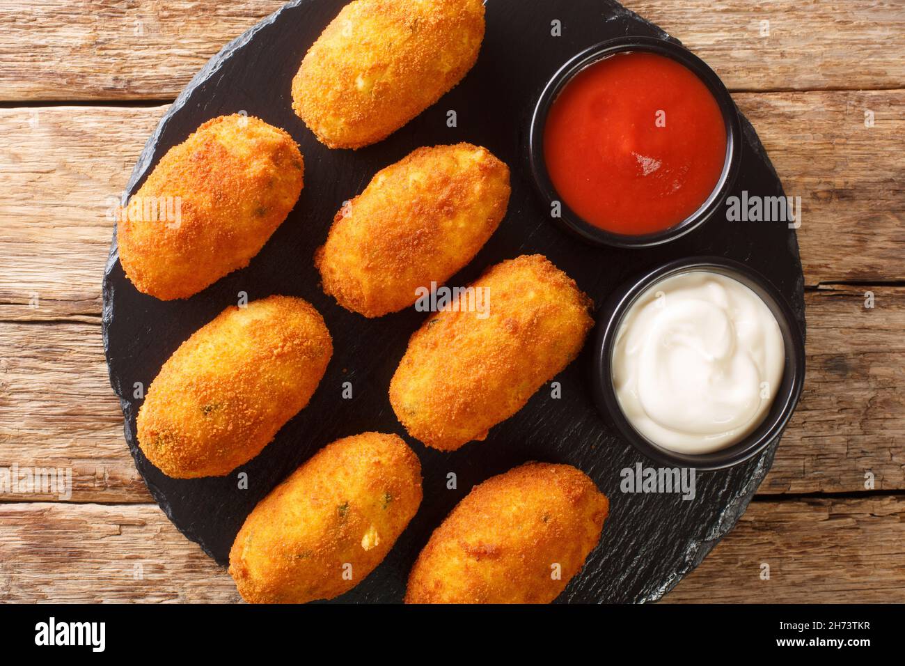 Croquetas de Bacalao Crocchette di merluzzo con salse da vicino nel piatto di ardesia sul tavolo. Vista dall'alto orizzontale Foto Stock