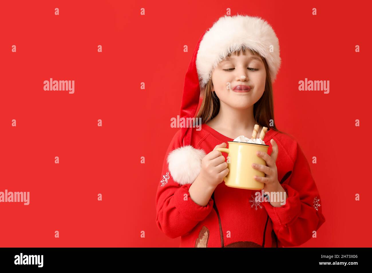 Bambina con tazza di cacao caldo su sfondo a colori Foto Stock