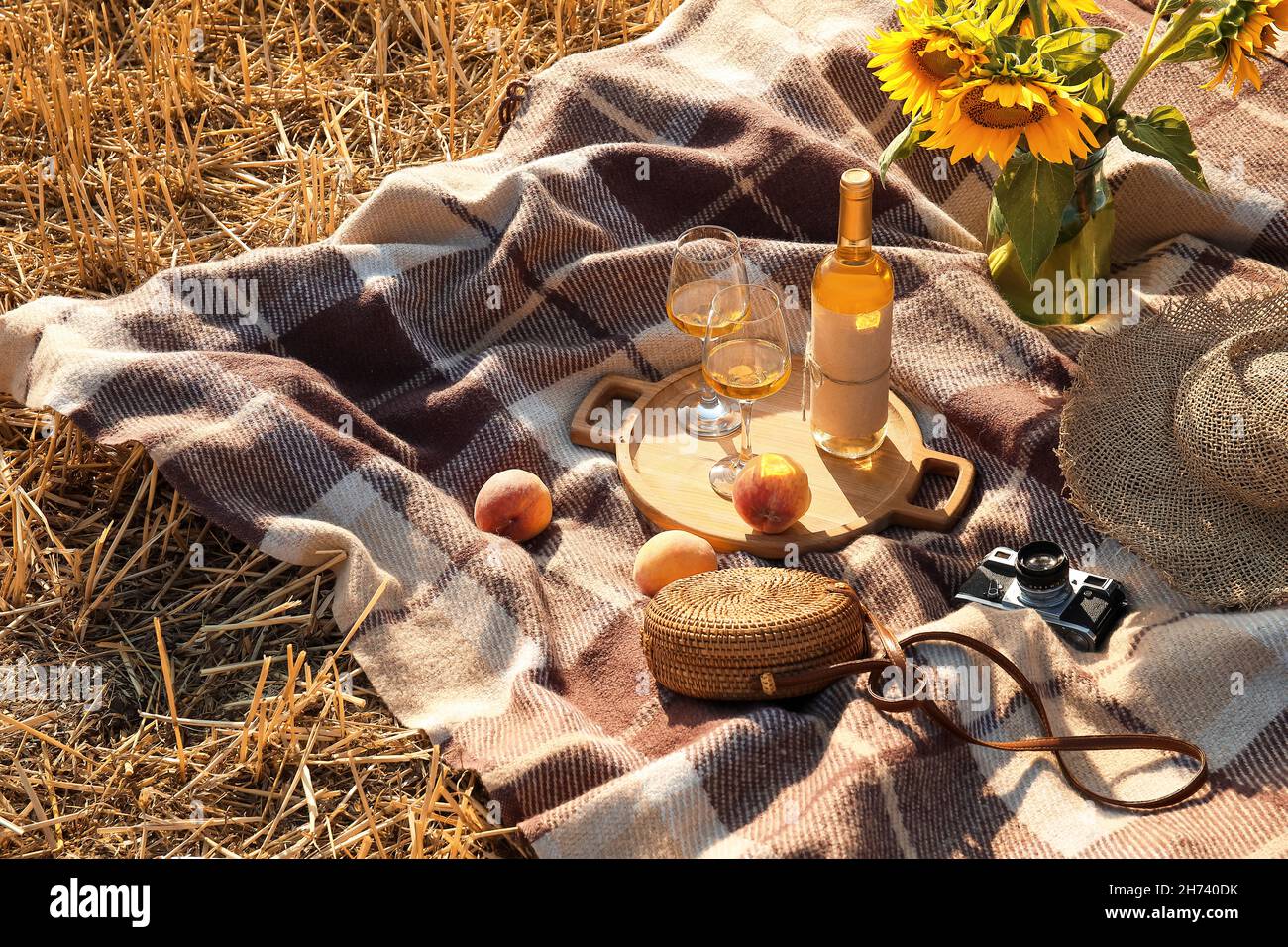 Picnic festivo con girasoli e vino sul campo di grano Foto Stock
