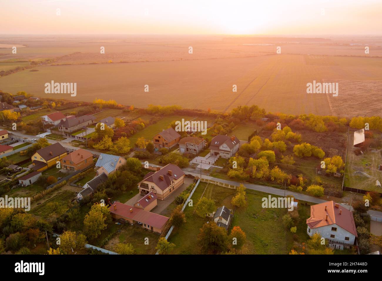 Bella vista aerea dall'alto del villaggio rurale con case e strade, campi arati, prati Foto Stock