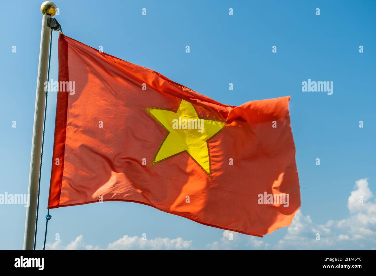 Primo piano della bandiera nazionale rossa del Vietnam con una stella d'oro nel mezzo, volando nel cielo Foto Stock
