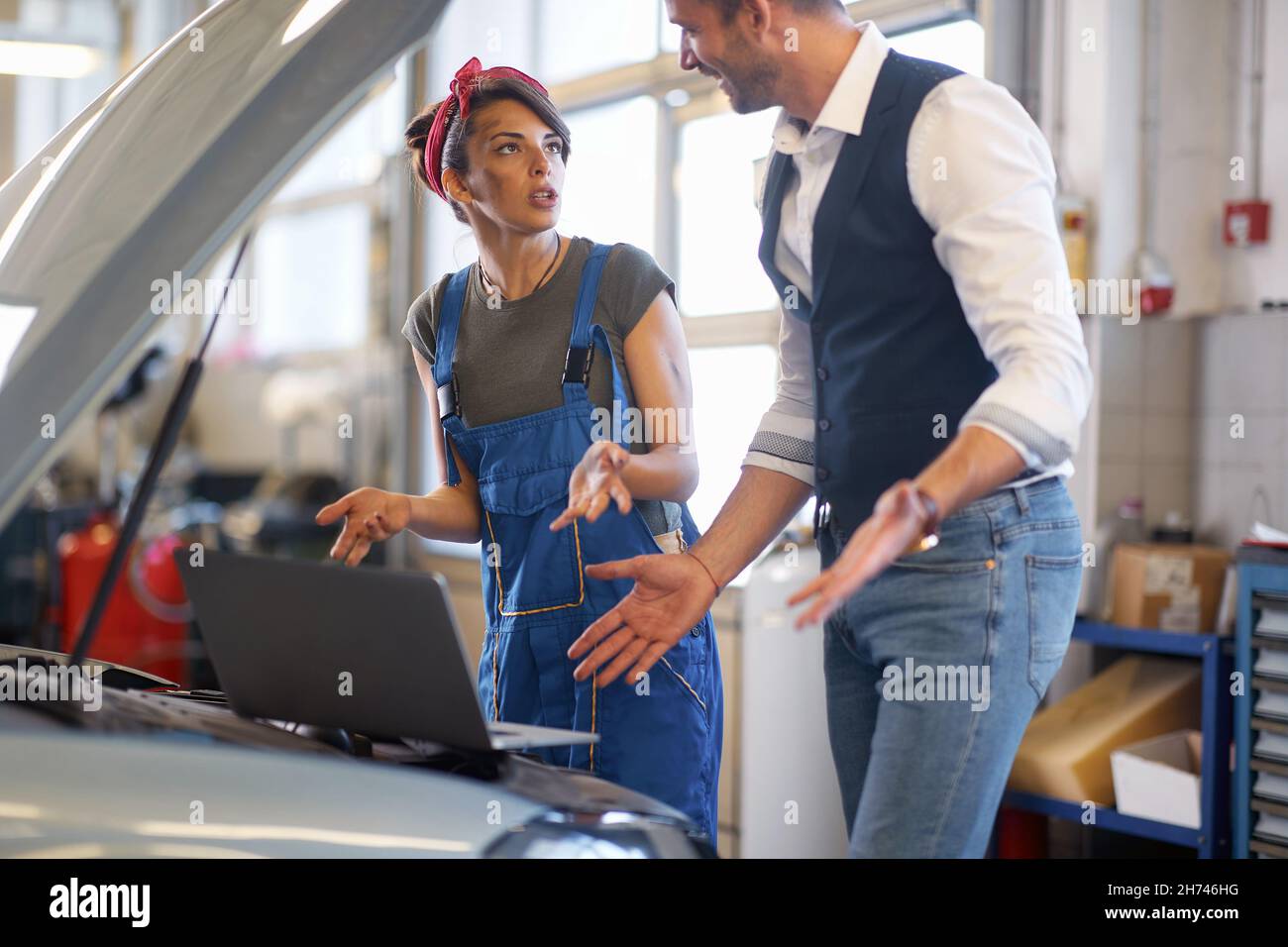 La meccanica femminile comunica con il cliente sorridente Foto Stock