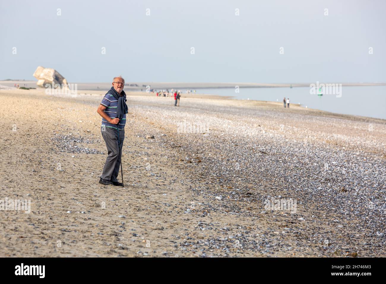 Uomo anziano che cammina con la canna sulla spiaggia di Hourdel. Baia di Somme, Francia Foto Stock