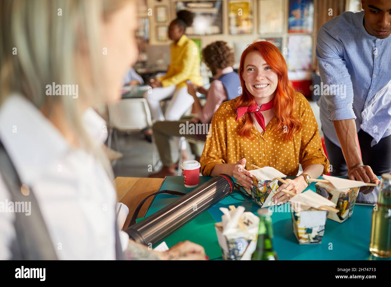 carina femmina caucasica rossa che parla e sorride con un collega al lavoro, che ha una pausa pranzo, mangiare cibo cinese Foto Stock