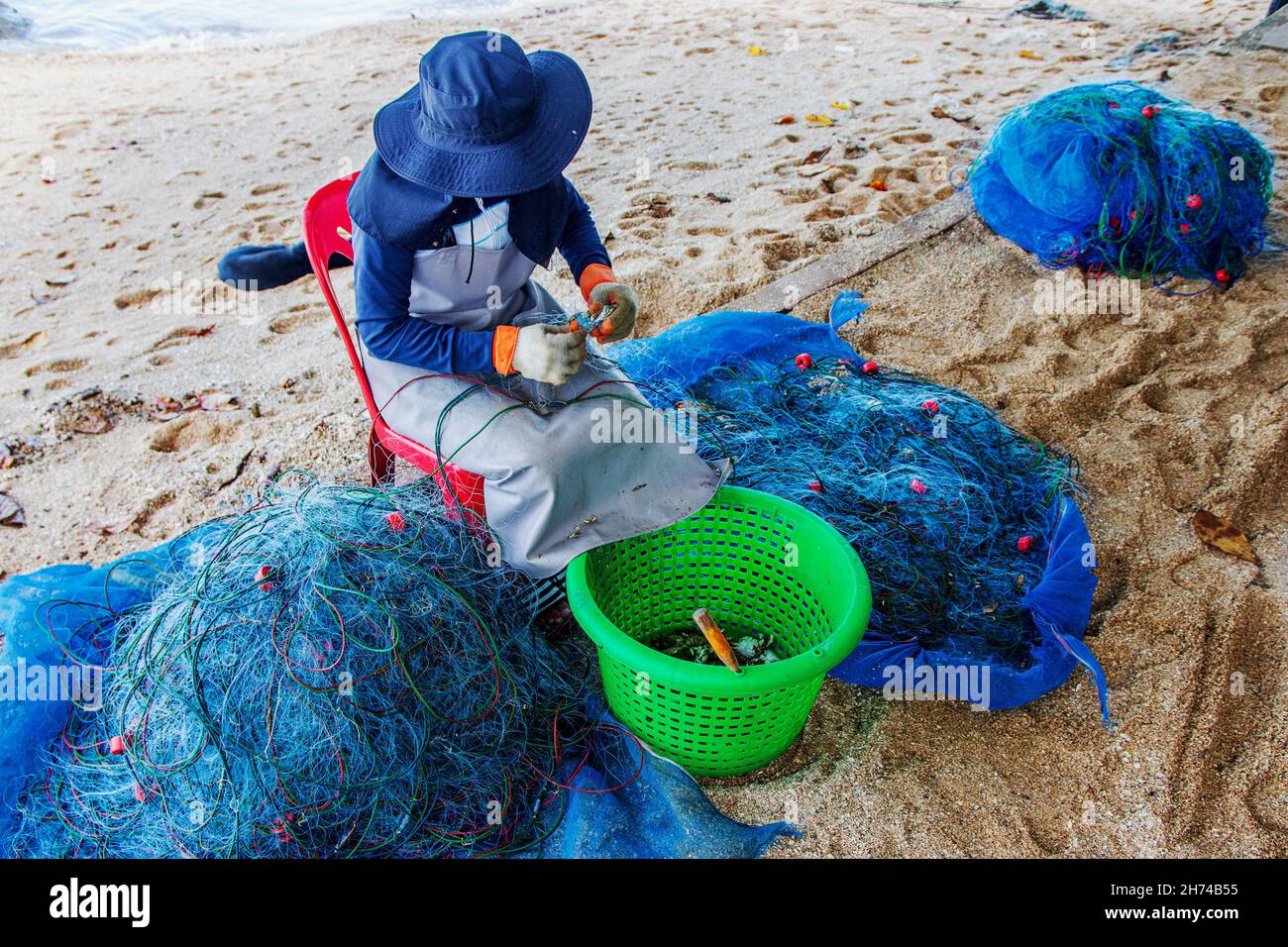 Riparazione e ispezione di una rete da pesca in spiaggia Foto Stock