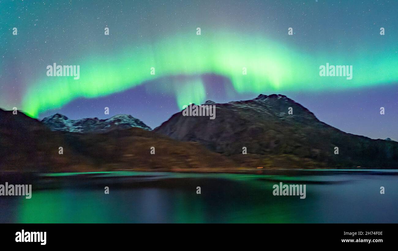 Durch den Raftsund mit dem Postschiff, unter wunderschönen Nordlichtern. Tanzende Aurora Borealis in Grün, Gelb und Pink in den Lofoten, Norwegen. Foto Stock