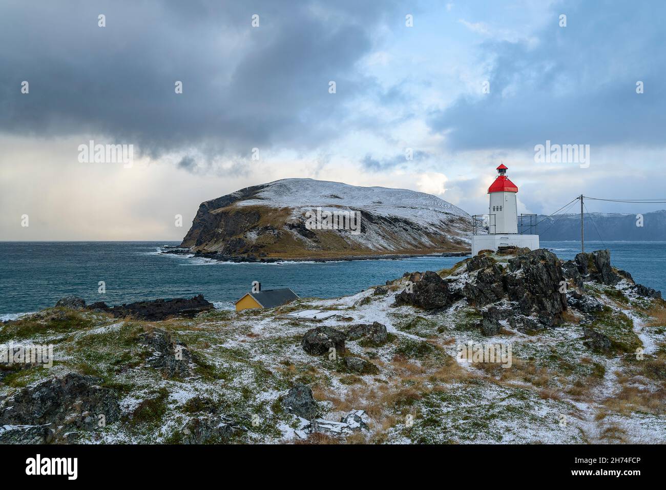 Sturmfront bei Kamøyvær auf Magerøya, Norwegen, mit der Insel Gáhpesuolu. Wilde Küste mit rot weissem Leuchtturm, gelbem Gras und brechenden Wellen. Foto Stock