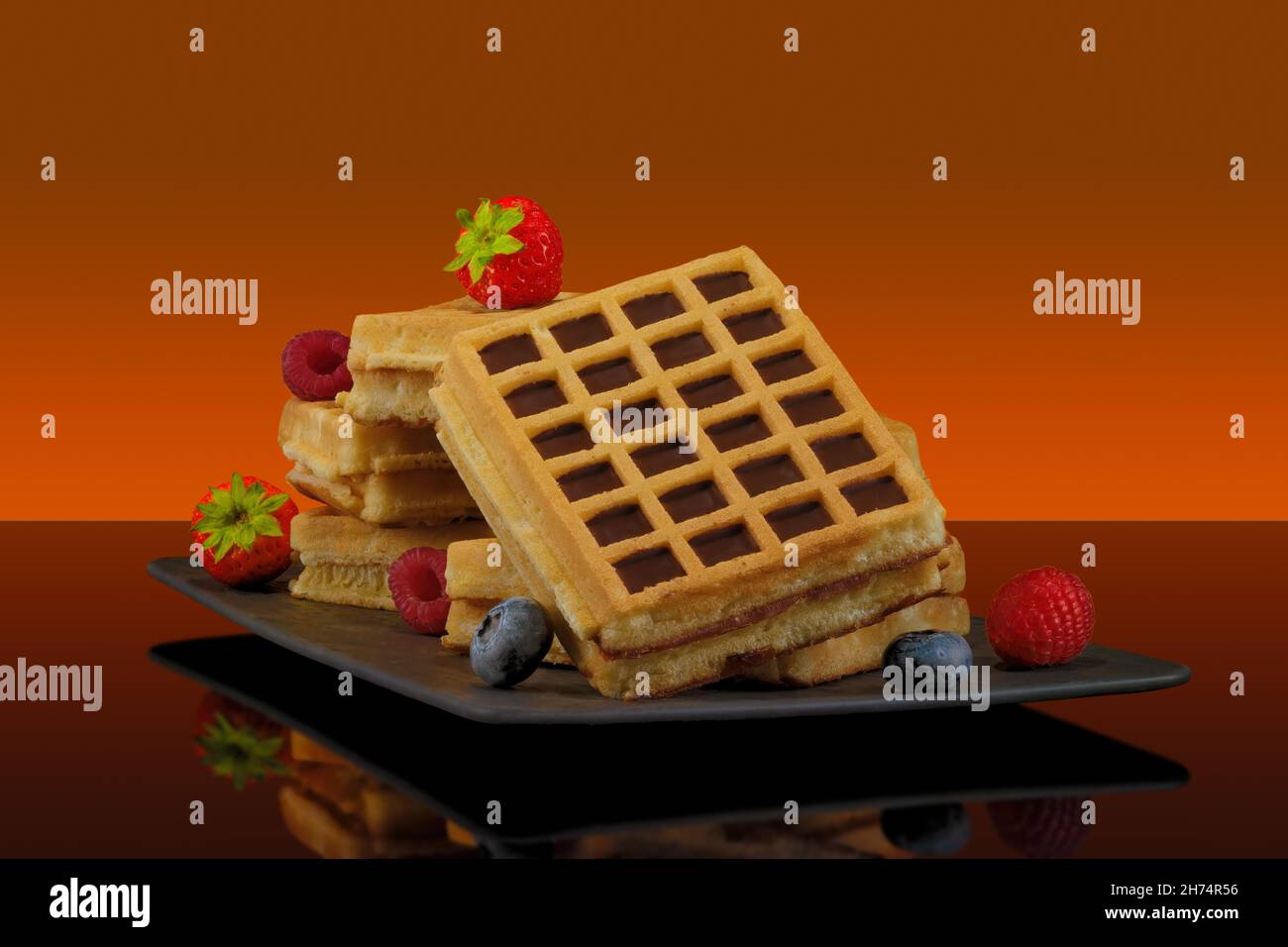 Waffle con frutta e sciroppo d'acero su sfondo colorato Foto Stock