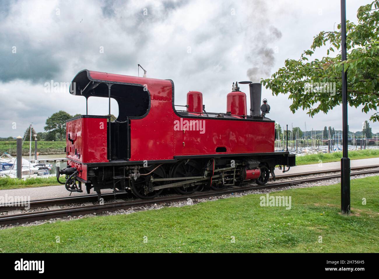 Vecchio treno a vapore rosso sul mare con barche a Picardie, Francia Foto Stock