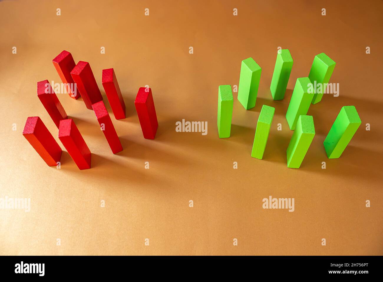 Blocchi di legno rosso e verde su sfondo colorato. Conflitto tra due gruppi. Concetto di concorrenza e concorrente nel settore commerciale. Foto Stock