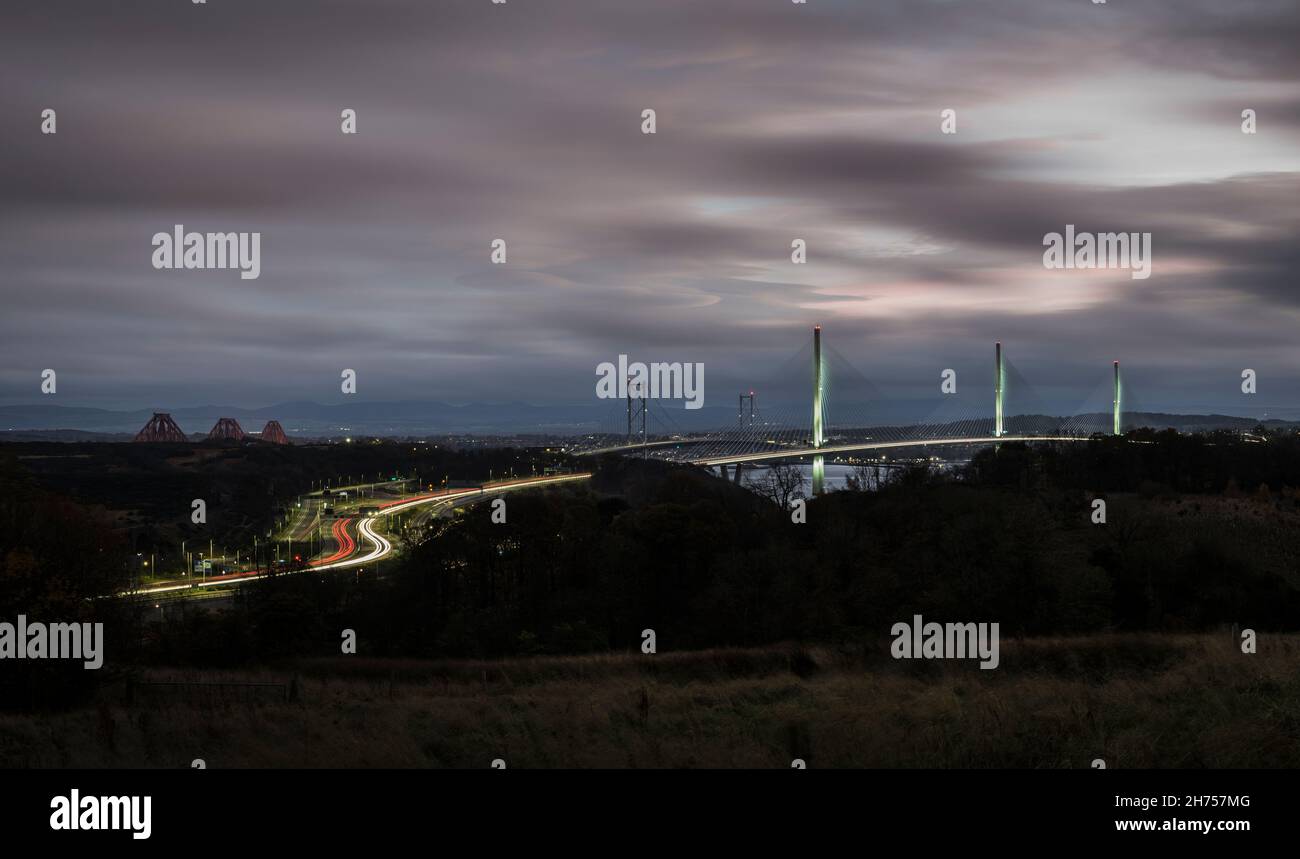 Percorsi a semaforo in movimento sull'autostrada M90 in Scozia con attraversamento del Queensferry illuminato e altri ponti stradali e ferroviari sullo sfondo. Foto Stock