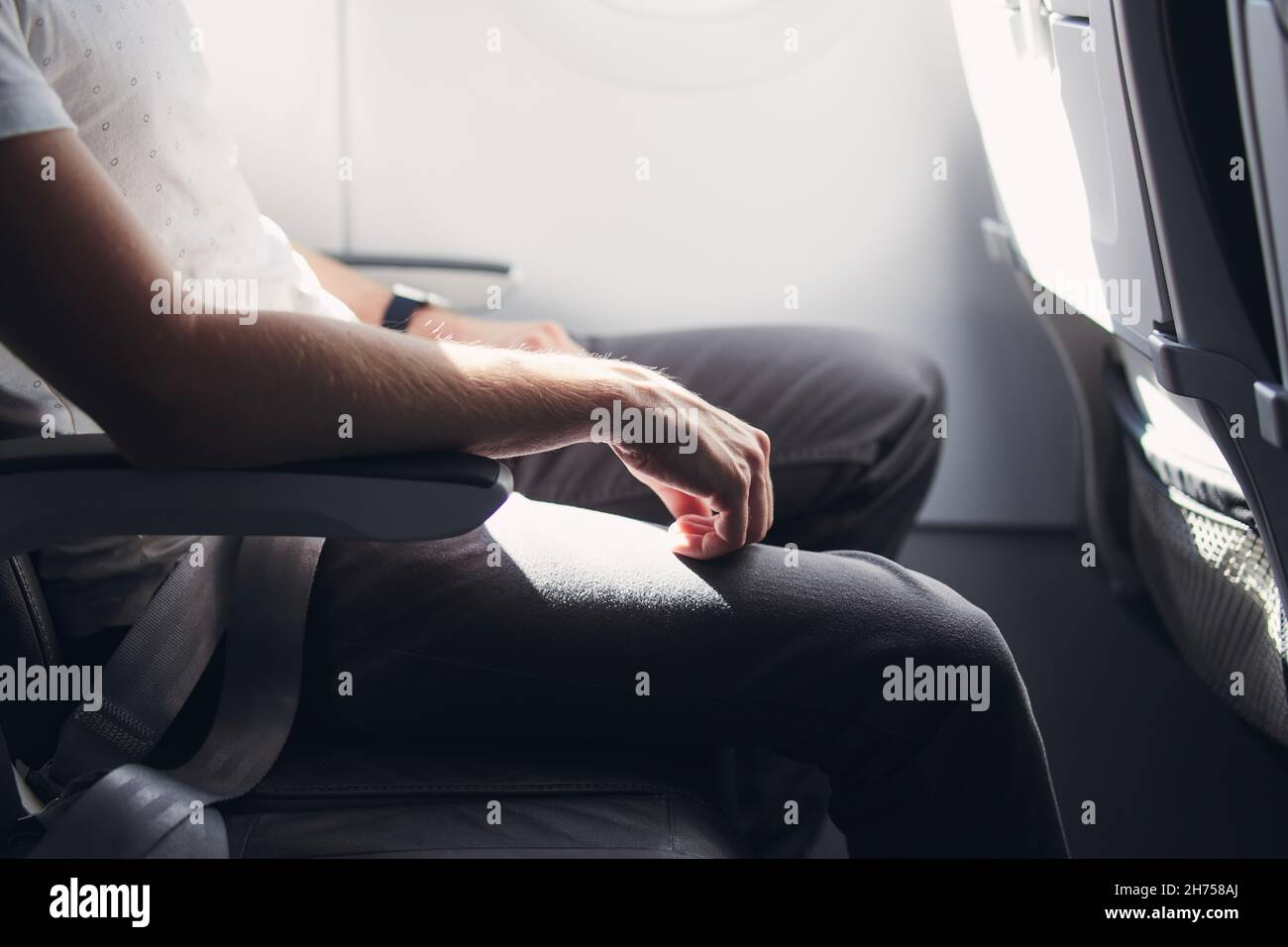 Uomo che riposa durante il volo. Spazio per le gambe tra i sedili in aeroplano commerciale. Foto Stock