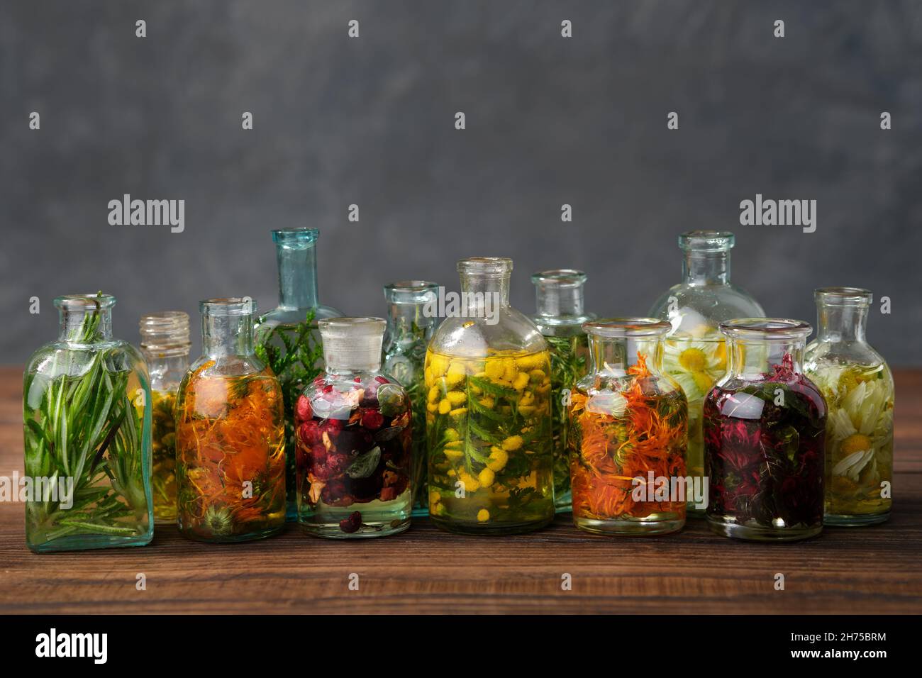 Bottiglie di olio essenziale o infusione di erbe medicinali e bacche - rosmarino, calendula, tansy, thuja, timo, bergamotto, camomilla. Piante curative, Foto Stock