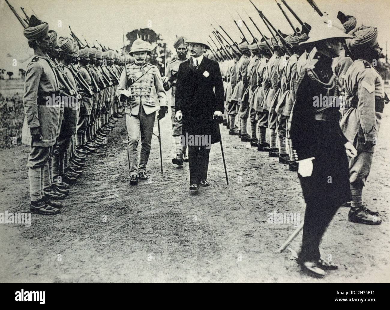 Una visione storica dei soldati indiani coloniali britannici in parata in fase di revisione da parte di ufficiali britannici e di un amministratore civile. C. 1914. Foto Stock