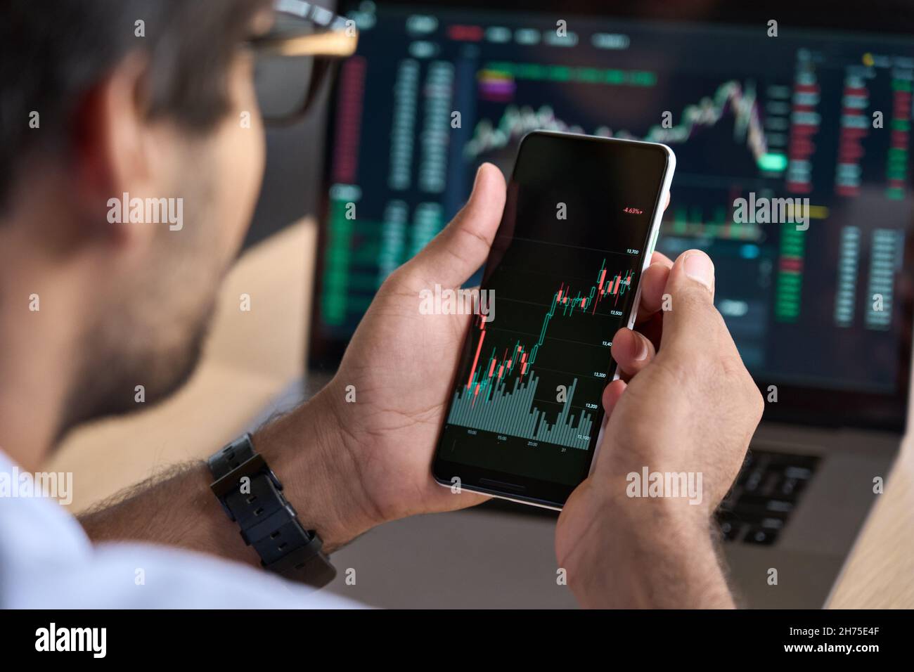 Broker trader tramite telefono che analizza i dati delle tabelle di negoziazione del mercato azionario utilizzando app. Foto Stock