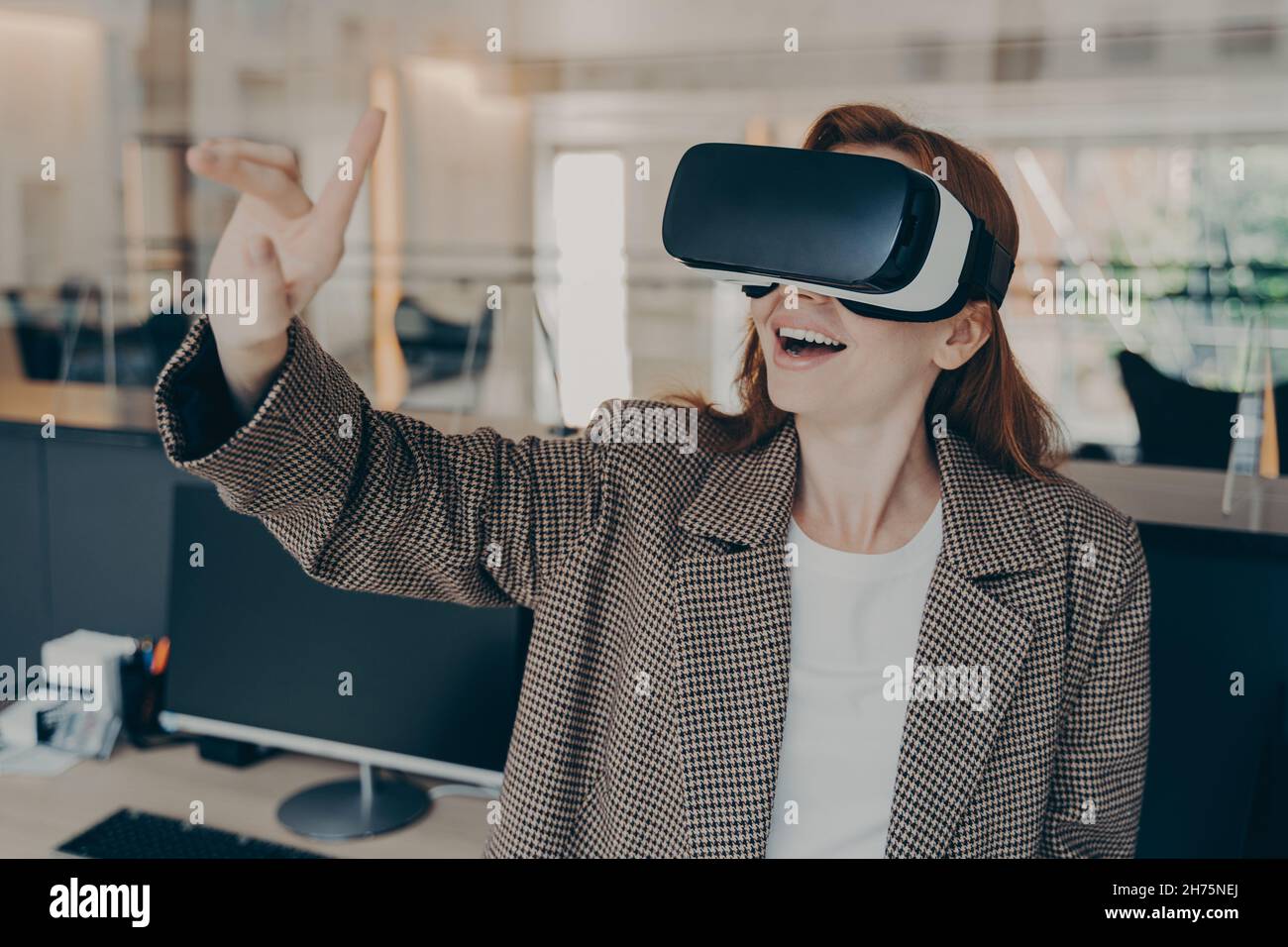 Il project manager femminile è entusiasta di rivedere il gioco della realtà virtuale mentre lavora in ufficio Foto Stock