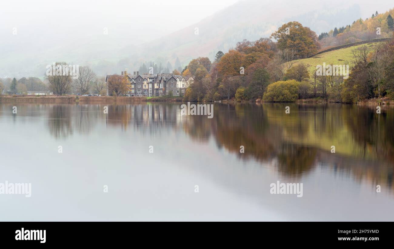 Una suggestiva mattinata autunnale a Grasmere, nel Parco Nazionale del Distretto dei Laghi, con l'Hotel Daffodil che si riflette nelle calme acque del lago. Foto Stock