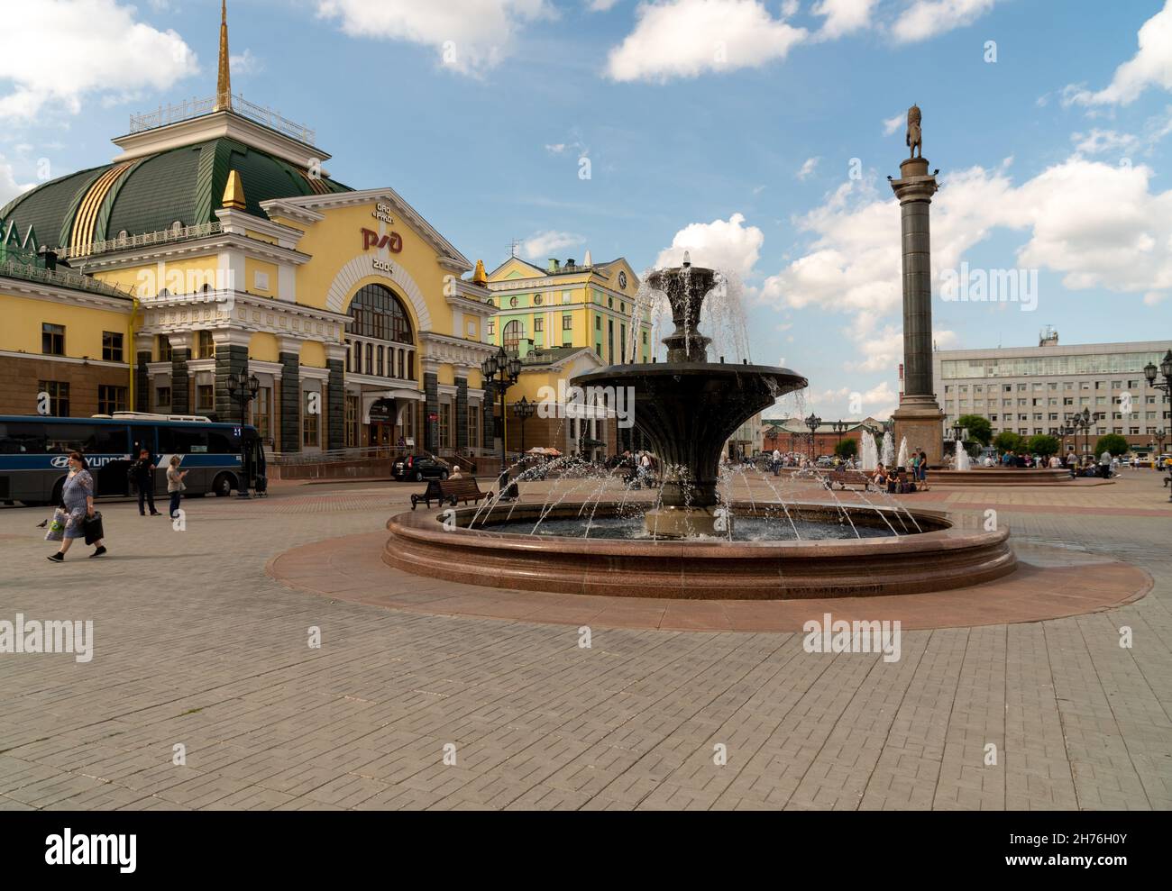 Piazza della stazione di fronte alla stazione ferroviaria principale della città con fontane e un pilastro con il simbolo della città. Foto Stock