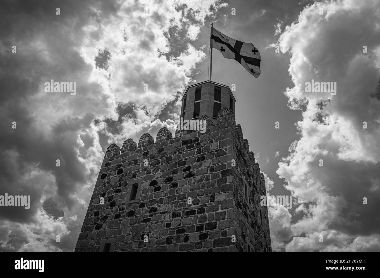 Castello medievale di Rabati con una bandiera georgiana svolazzante contro il cielo nuvoloso blu. Akhaltsikhe, Georgia. Bianco e nero. Foto Stock