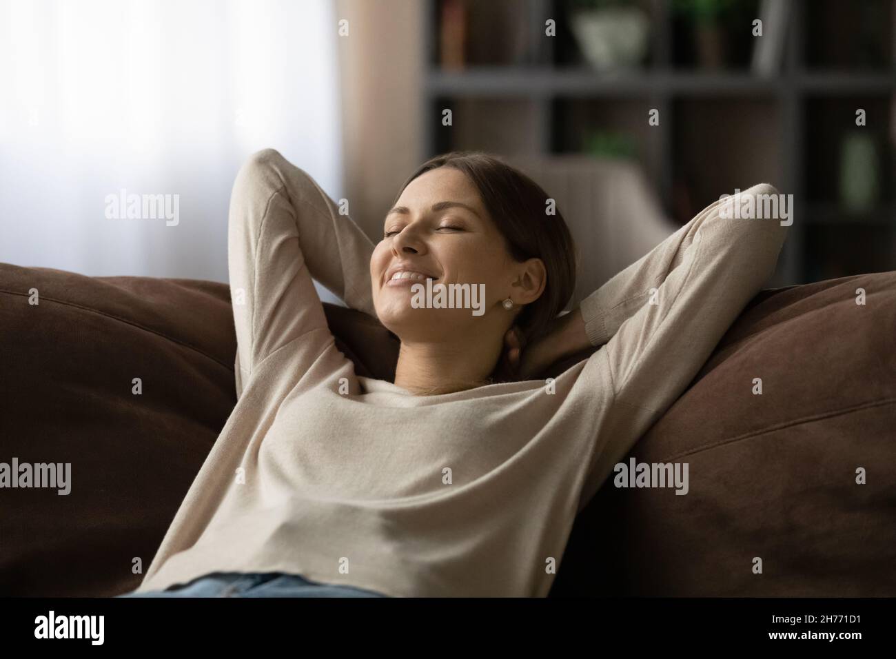 La donna si appoggia sul divano chiudendo gli occhi respirare aria fresca condizionata Foto Stock