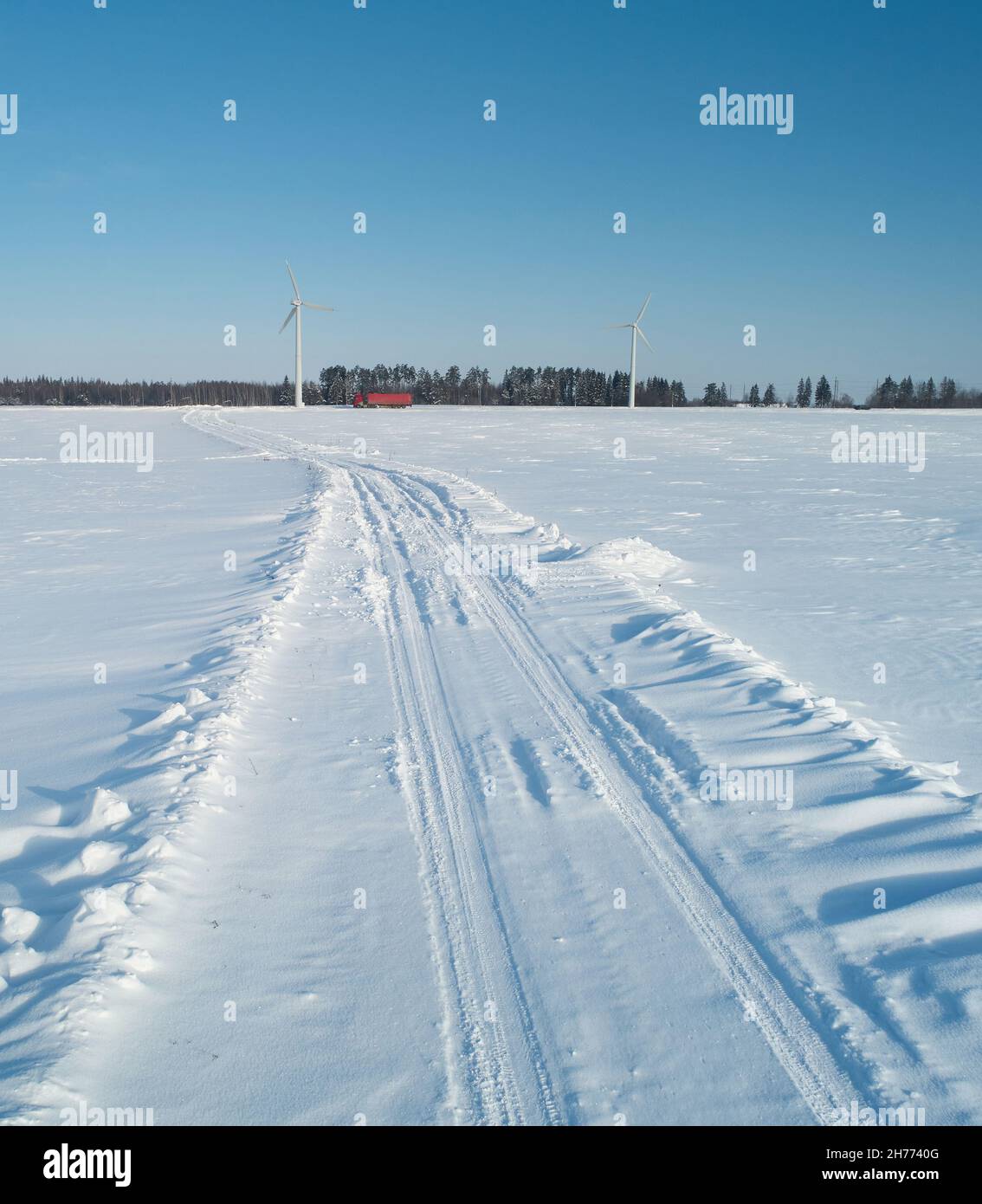 Strada in campo innevato con sfondo industriale sul retro Foto Stock