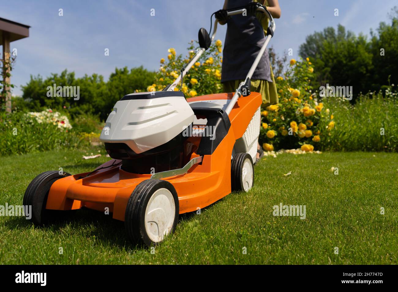Una donna giardiniere sta rifilando l'erba con il tagliaerba, vista dal basso Foto Stock