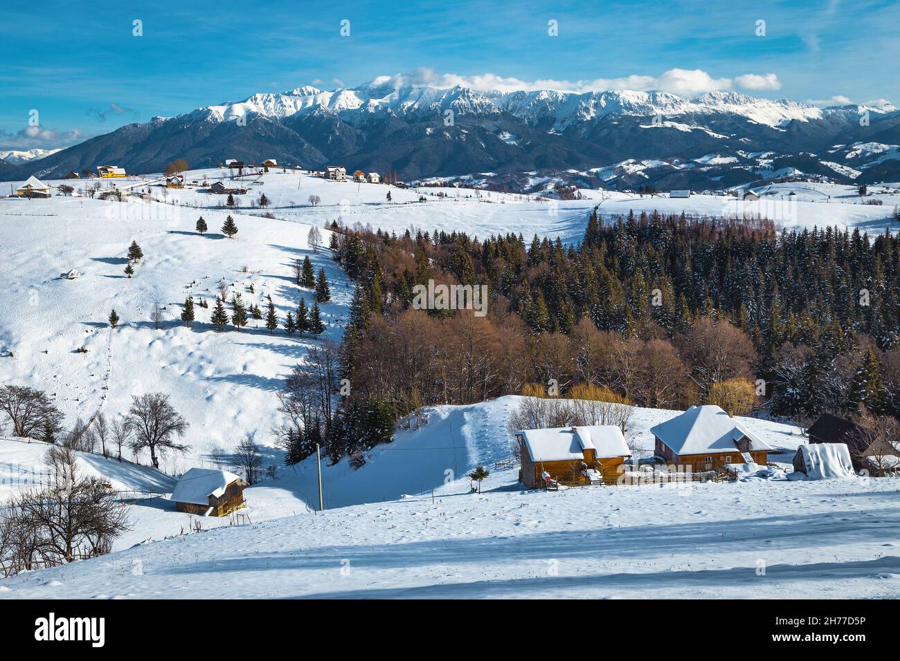 Pittoresco villaggio alpino e bellissimo paesaggio invernale con montagne innevate sullo sfondo, Pestera villaggio, Romania, Europa Foto Stock